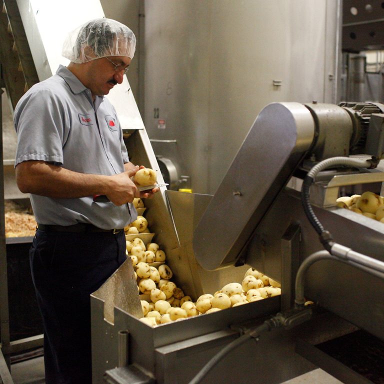 man peeling potatoes in factory