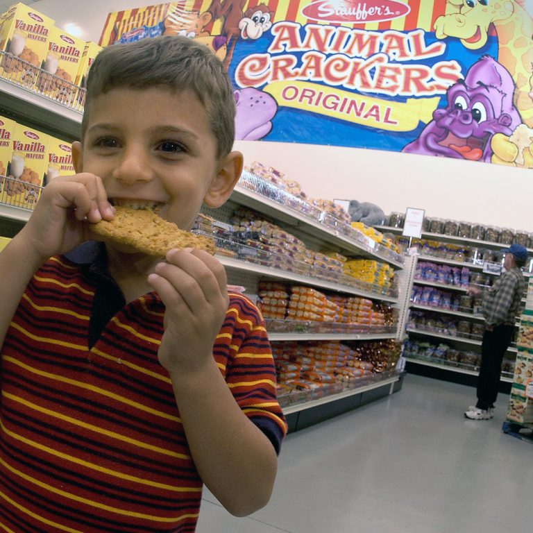 little boy smiling and eating a cookie at stauffers cookie outlet